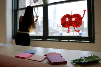 موظفة في شركة إعلامية تشكل صورة على نافذة  في مكتب الشركة