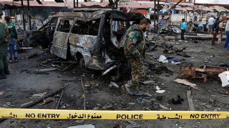 عسكري سوري يمشي بجانب حافلة دمرها انفجار