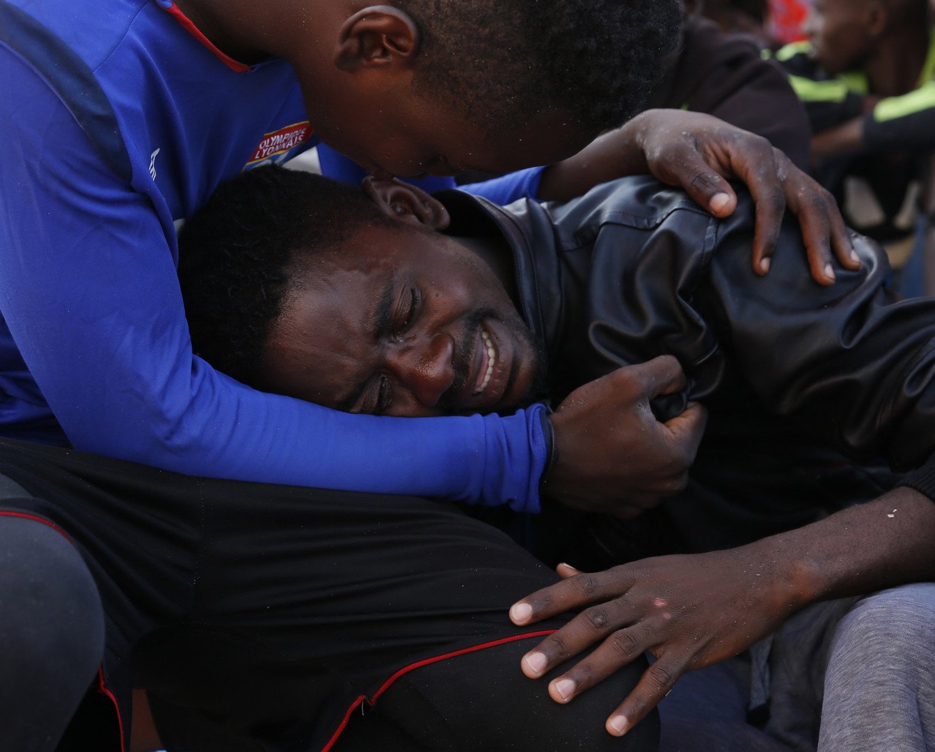 مهاجر يهدئ من روع رفيقه بعد ركوب سفينة الإنقاذ