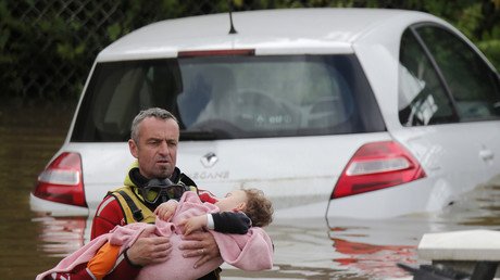 رجل من فوج المطافئ الفرنسي ينقذ طفلا في منطقة مغمورة بالفيضان