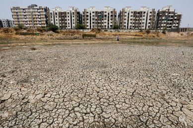 مبان ترى خلف بحيرة جفت من جراء الحر وتكونت في طينها الشقوق