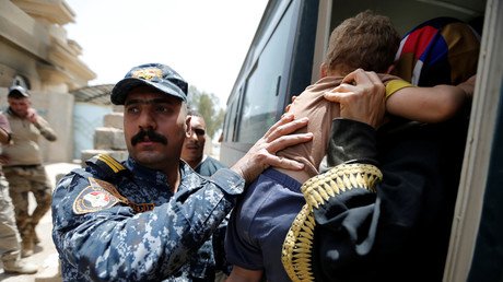 عنصر من القوات الأمنية العراقية يحمل طفلا في معرض مساعدته مجموعة من المدنيين الهاربين من المعارك قرب معسكر طارق  شرق الفلوجة