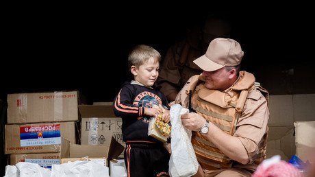 عسكري روسي يقدم حلويات لطفل سوري أثناء حملة توزيع المساعدات الإنسانية في المناطق السورية المنكوبة