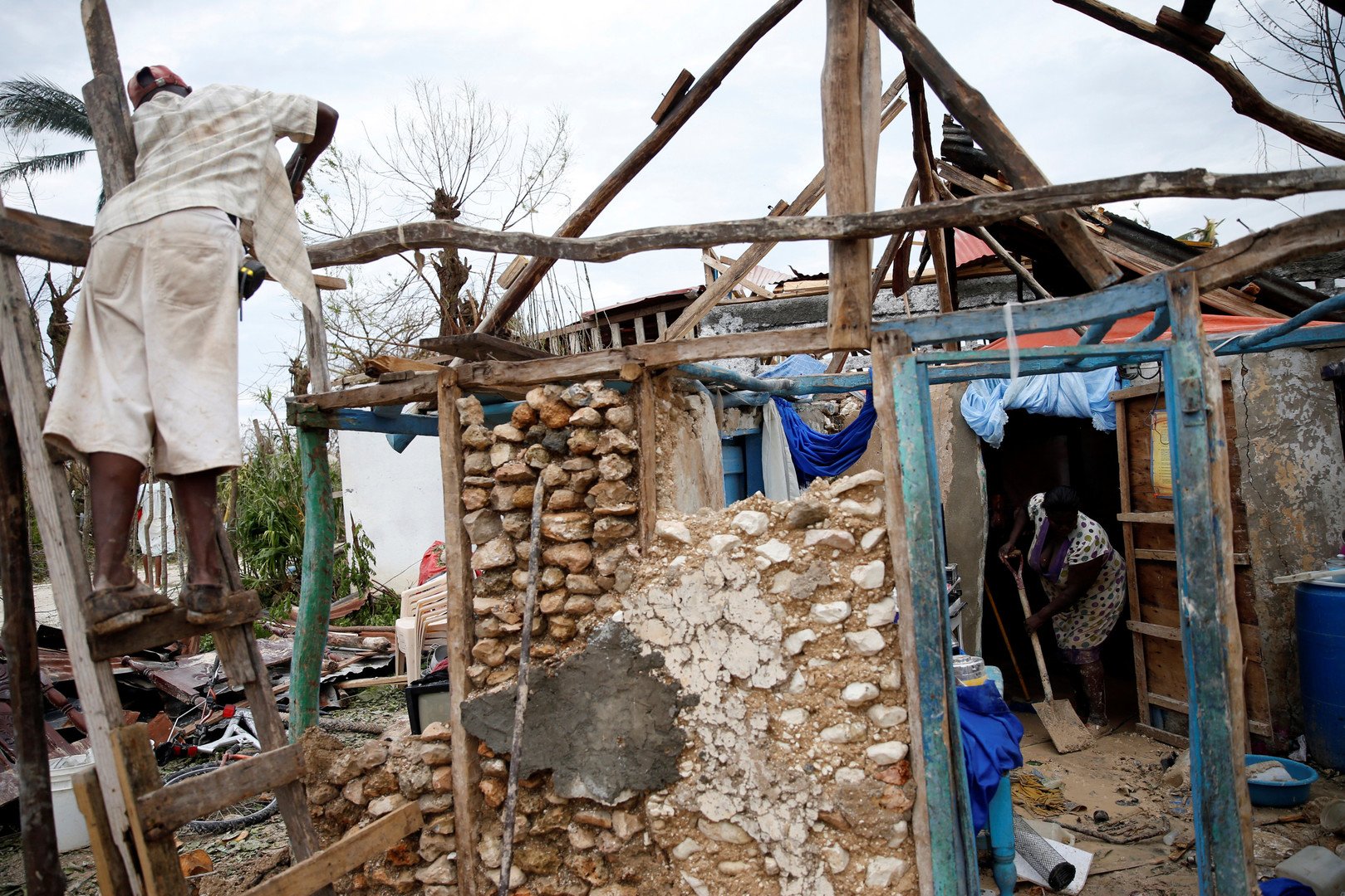 مواطنون يحاولون إزالة الأضرار الملحقة بمنزلهم جراء إعصار ماثيو بمدينة جيريمي في هايتي