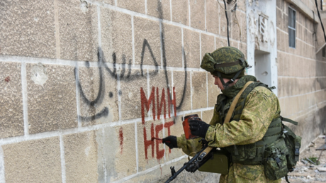 جندي روسي يكتب على جدار في أحد أحياء حلب الشرقية بالخط العريض "منطقة خالية من الألغام"