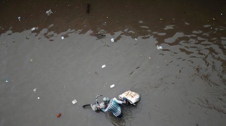 رجل يدفع دراجته خلال المياه التي تغمر الشوارع بعد هطول أمطار غزيرة في مدينة أحمد آباد في الهند. 27 يوليو 2017