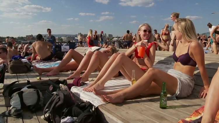 شاهد.. النرويجيون يتهافتون إلى الأنهار والبحيرات للاستمتاع بأشعة الشمس ودرجات الحرارة الدافئة