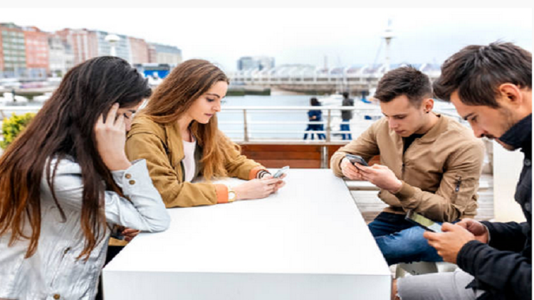 группа людей обсуждает что-то за столом, в руках у одного телефон