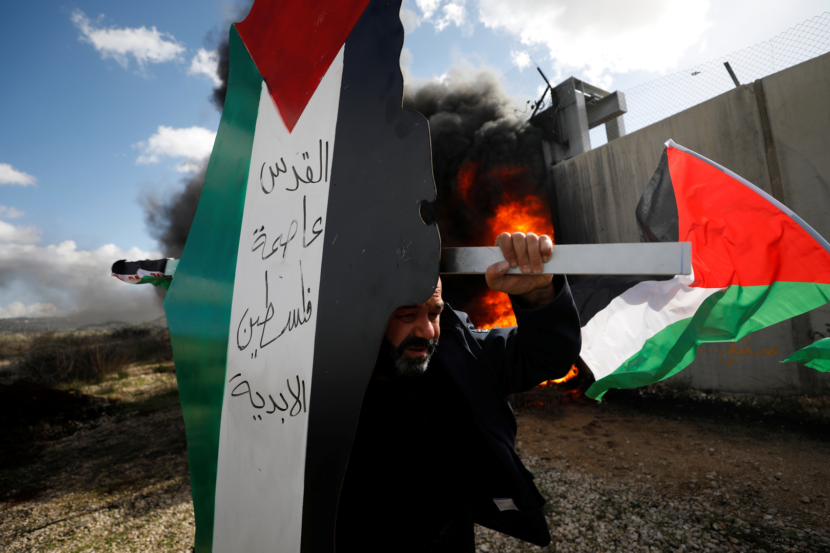 رجل يحمل خارطة عليها علم فلسطين