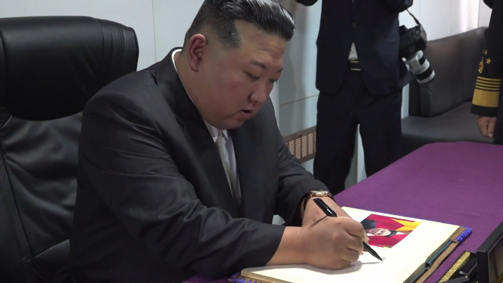 كيم يدوّن كلمة في دفتر زوار فرقاطة