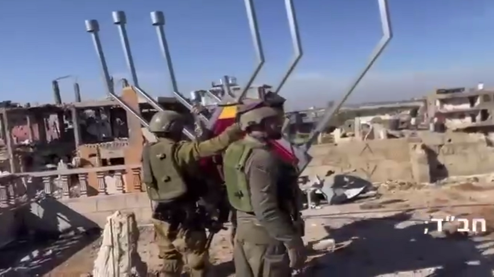 جنود إسرائيليون يقيمون شمعدان عيد الحانوكا على أحد أسطح مباني غزة المدمرة