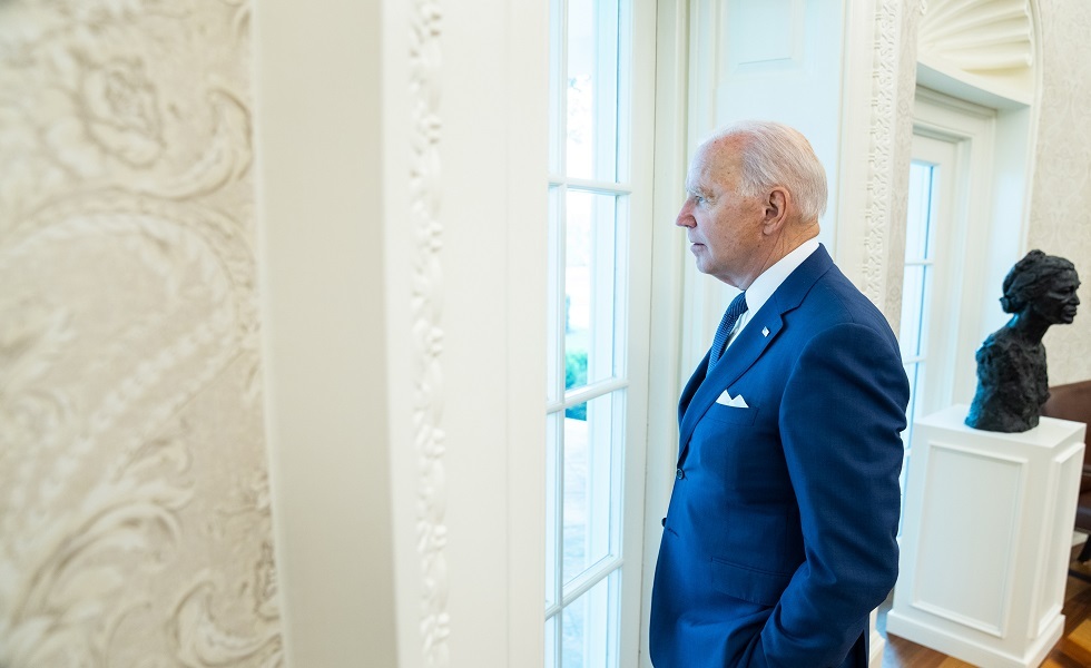 الرئيس جو بايدن ينظر من نافذة البيت الأبيض