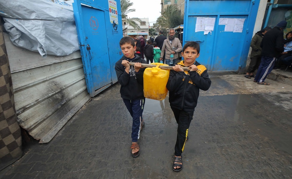 طفلان في غزة يحملان مياها للشرب بوسائل بدائية في ظل الدمار الذي أصاب البنى التحتية