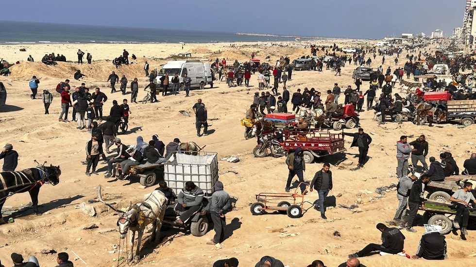 فلسطينيون ينتظرون مساعدات إنسانية على شاطئ مدينة غزة، الأحد، 25 فبراير، 2024.