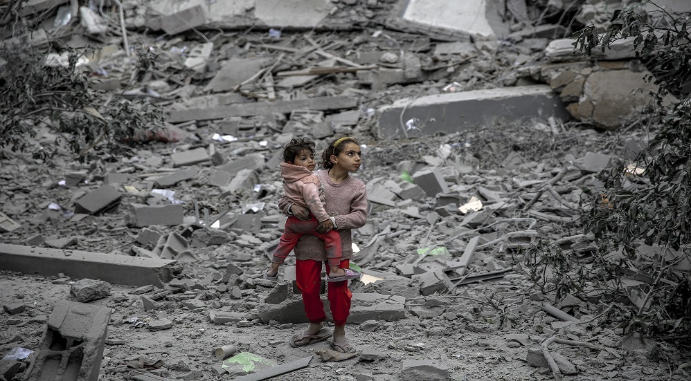 طفلة تحمل شقيقها الرضيع في أحد أحياء مدينة غزة المدمرة