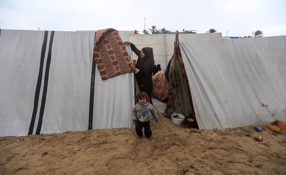 سيدة فلسطينية مع طفل في مخيمات النزوح المؤقت بقطاع غزة
