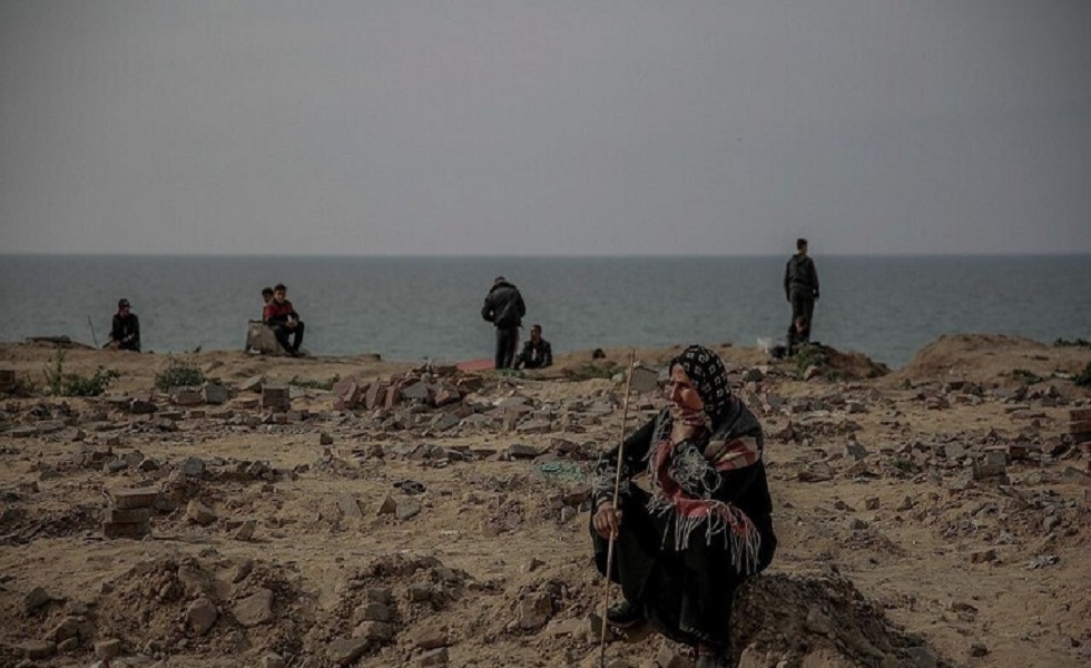سيدة فلسطينية تجلس قرب شاطئ غزة