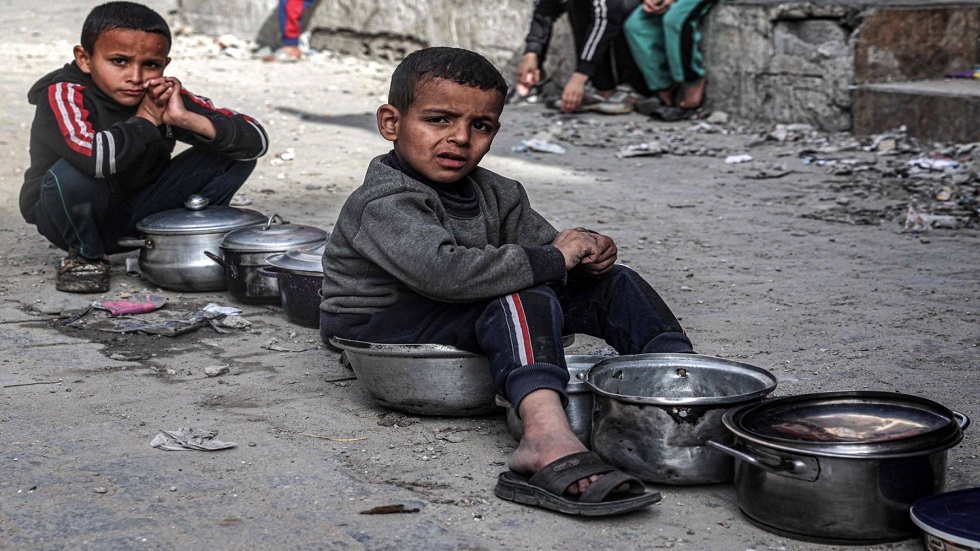 طفلان فلسطينيان ينتظران ملء أوعيتهم بالطعام من منظمة خيرية قبل ميعاد الإفطار في رفح
