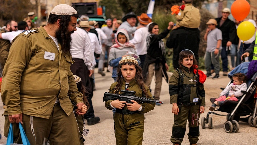 صبي إسرائيلي يحمل لعبة على هيئة بندقية هجومية في مدينة الخليل بالضفة الغربية