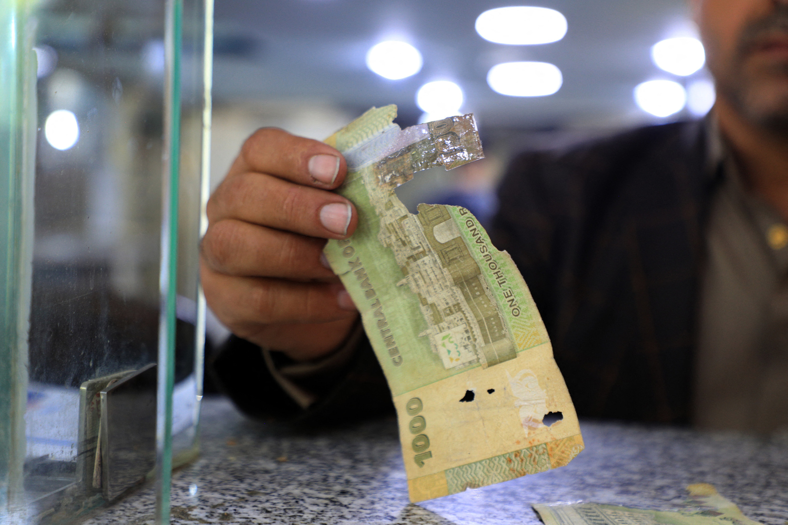 رجل يحمل ورقة نقدية ممزقة من الريال اليمني في مكتب صرف العملات في العاصمة اليمنية صنعاء