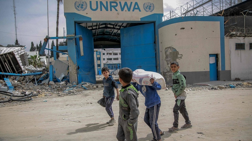 أطفال يحملون مساعدات غذائية أمام مركز الأونروا في مدينة غزة