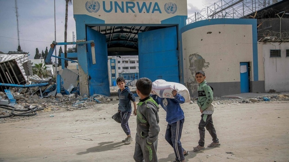أطفال يحملون مساعدات غذائية أمام مركز الأونروا في غزة