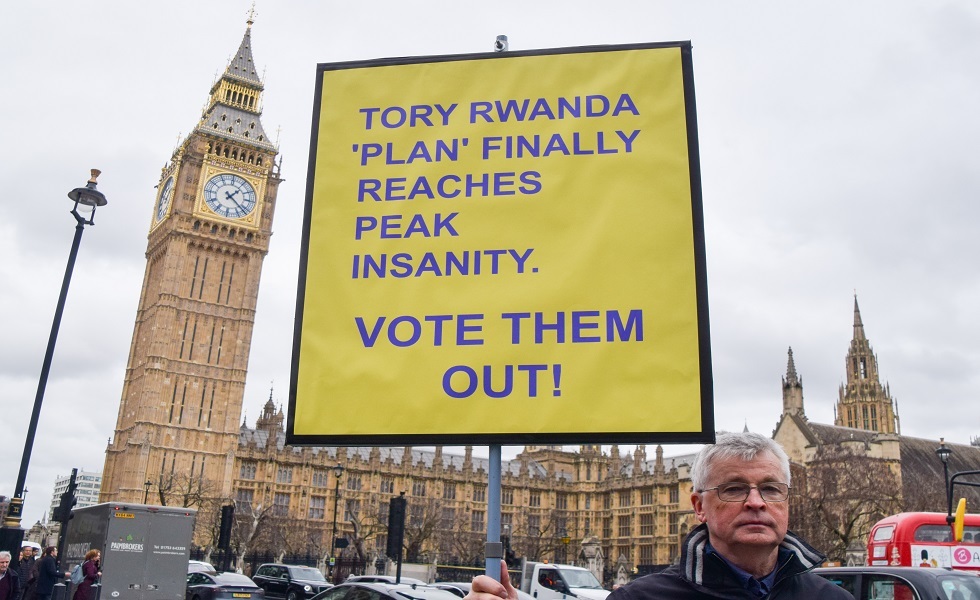 متظاهر يحمل لافتة تنتقد خطة الحكومة لترحيل مهاجرين إلى رواندا - لندن، بريطانيا.