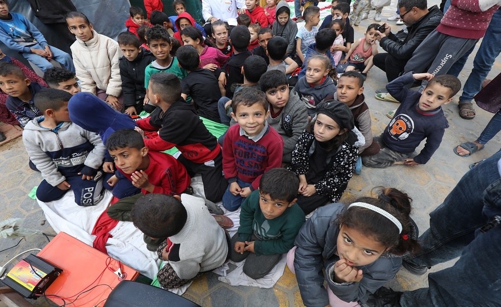 أطفال فلسطينيون يشاهدون الرسوم المتحركة في دير البلح مع استمرار الحرب على غزة- قطاع غزة