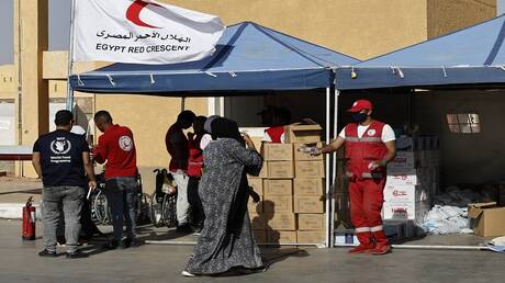 متطوعون في الهلال الأحمر المصري يقدم المساعدة للاجئين سودانيين عند وصولهم إلى معبر بري بين مصر والسودان