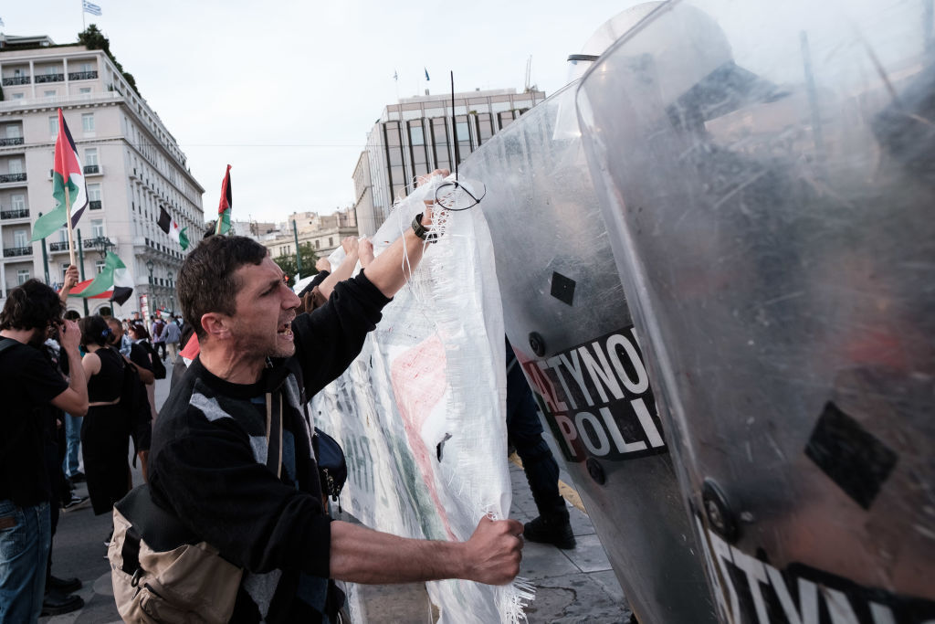 متظاهر داعم لفلسطين يقف في وجه عناصر الشرطة اليونانية، أثينا، 7 مايو 2024.
