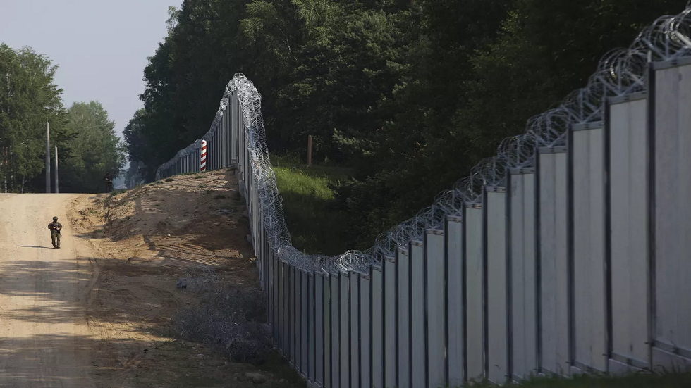 أحد حرس الحدود البولنديين يسير على طول السياج الفاصل  بين بولندا وبيلاروس