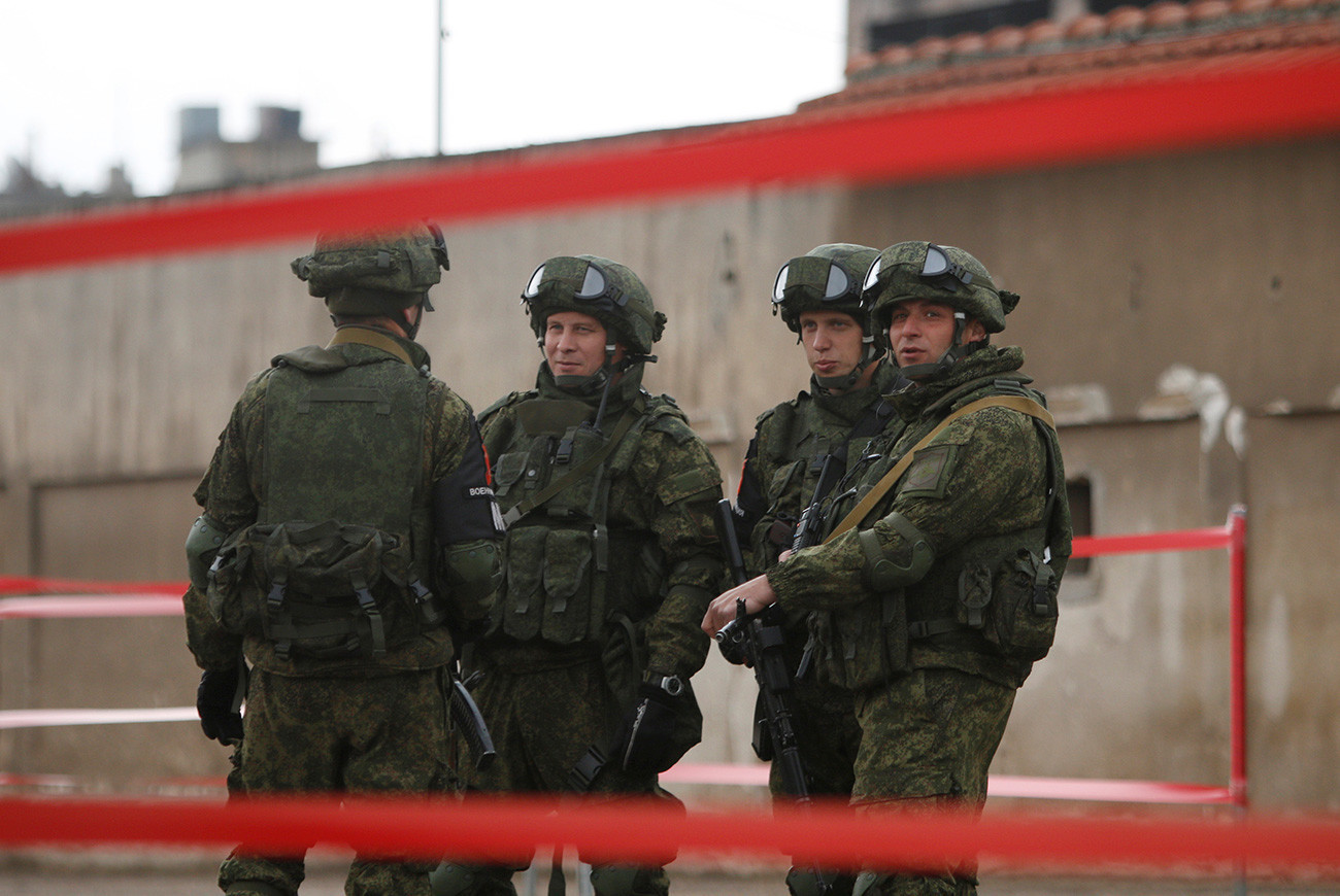 Soldados russos reunidos enquanto insurgentes e suas famílias evacuam o distrito sitiado de Waer, na cidade síria de Homs, após um acordo entre rebeldes e o Exército do país, em 18 de março de 2017