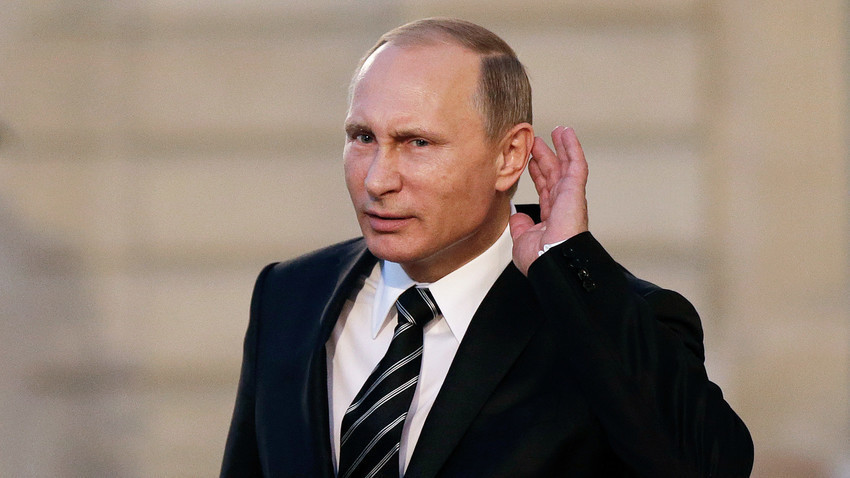 Владимир Путин се обидува да слушне новинарско прашање на враќање од средба, посветена на украинската криза во Елисејската палата во Париз.
