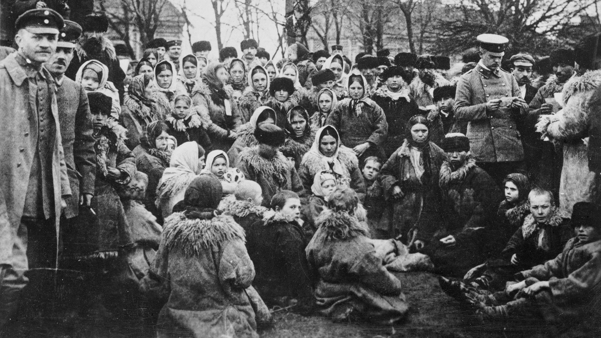 Crowd of the Jewish refugees in the open air in Russia. One of the three uniformed officials with them is examining their papers.