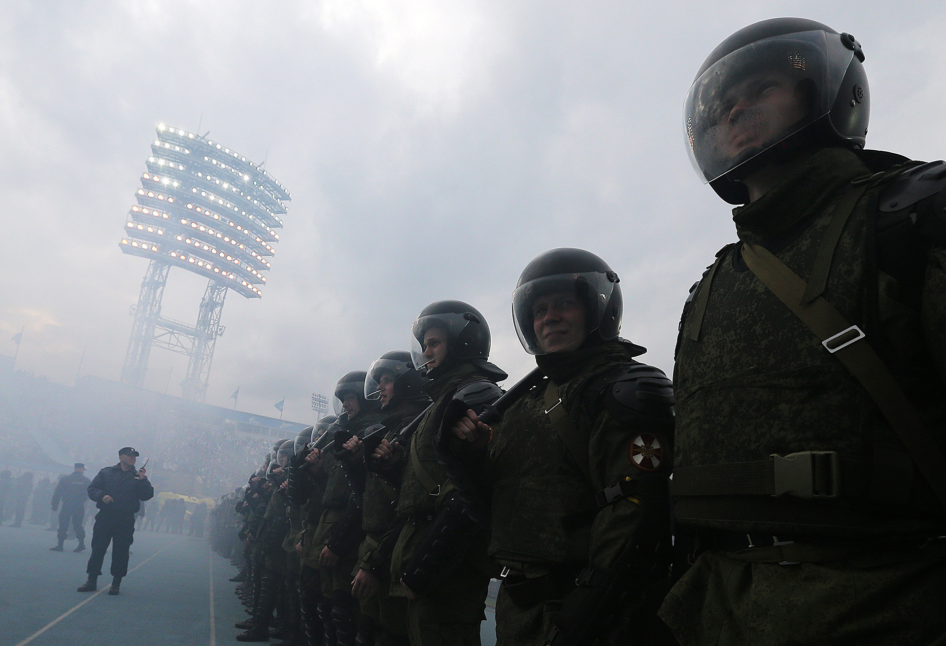 Policiais observam torcedores acendendo sinalizadores durante o Campeonato Russo.