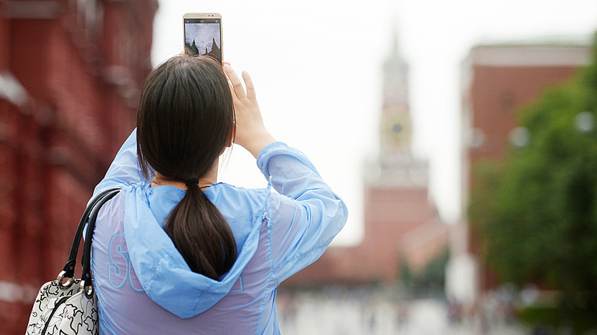 Seorang turis mengambil gambar Kremlin dengan ponselnya.
