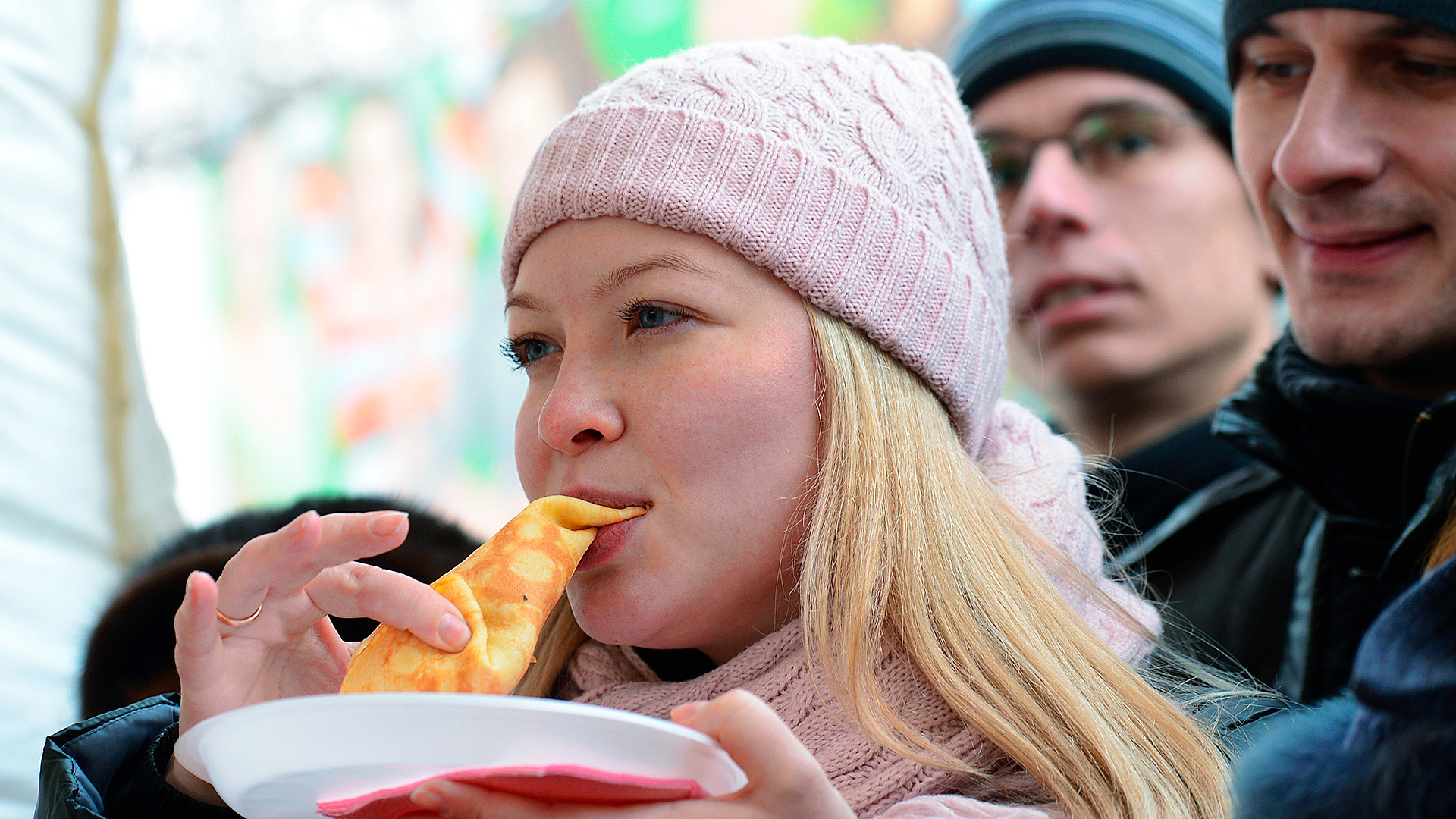 A young lady eats pancakes during Shrovetide festivities in Moscow's Gorky Park.