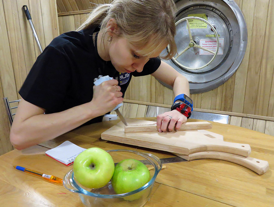 A homemade device from a wooden cutting board  to squeeze the tubes with space food.