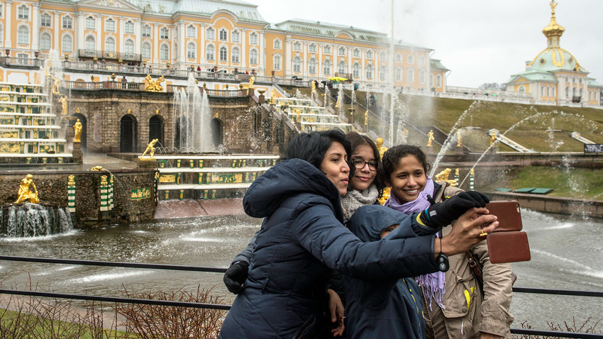 Beberapa wisatawan berfoto dengan latar belakang air mancur Bolshoi Kaskad saat pembukaan Peterhof untuk musim panas.
