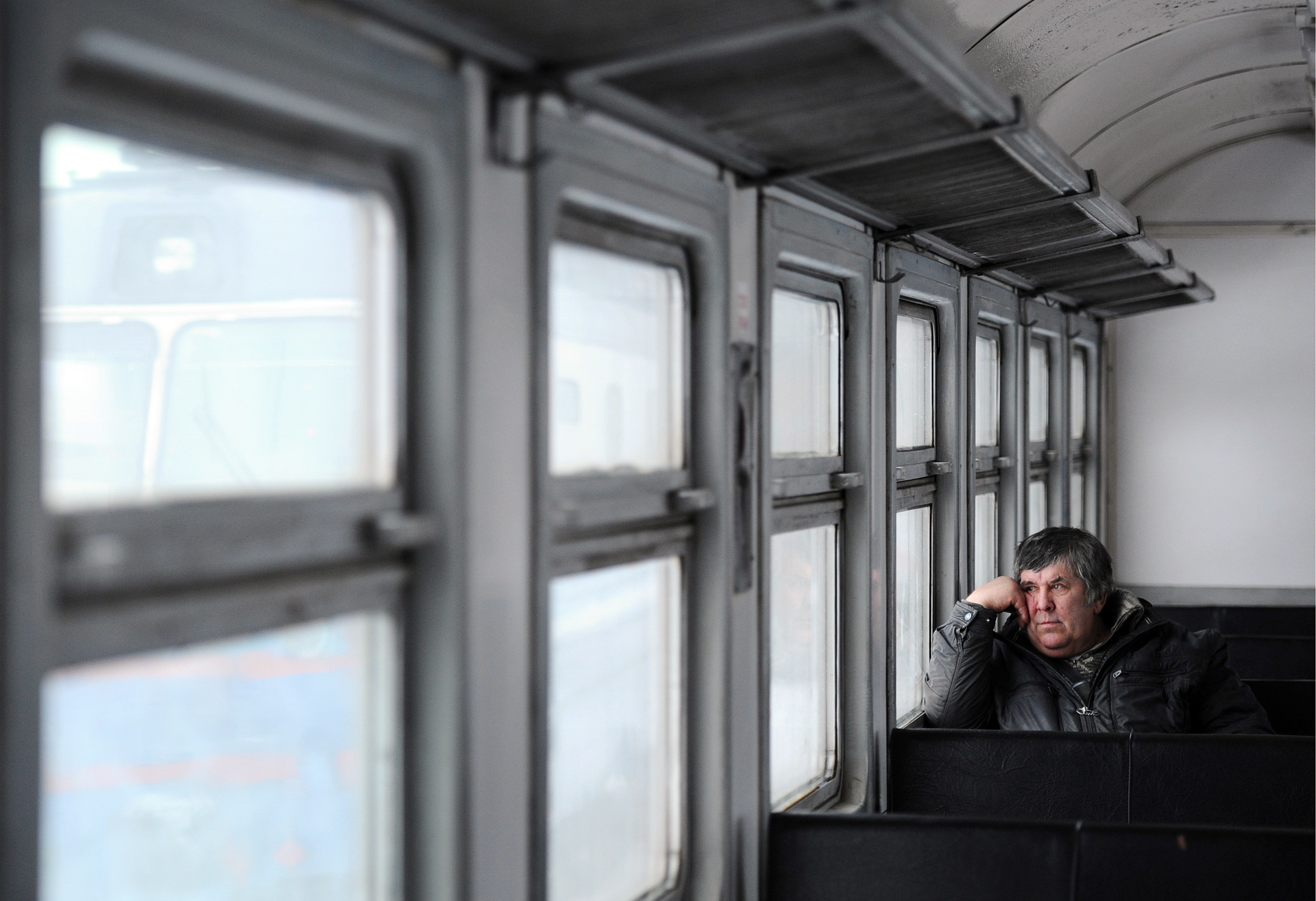 A man looks through the window as he sits in a commuter train. 