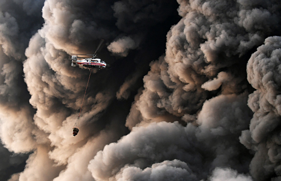 Руски хеликоптер за вонредни состојби носи вода низ облаци од чад додека пожарникарите се борат со пламенот во трговски центар во западното предградие на Москва.  