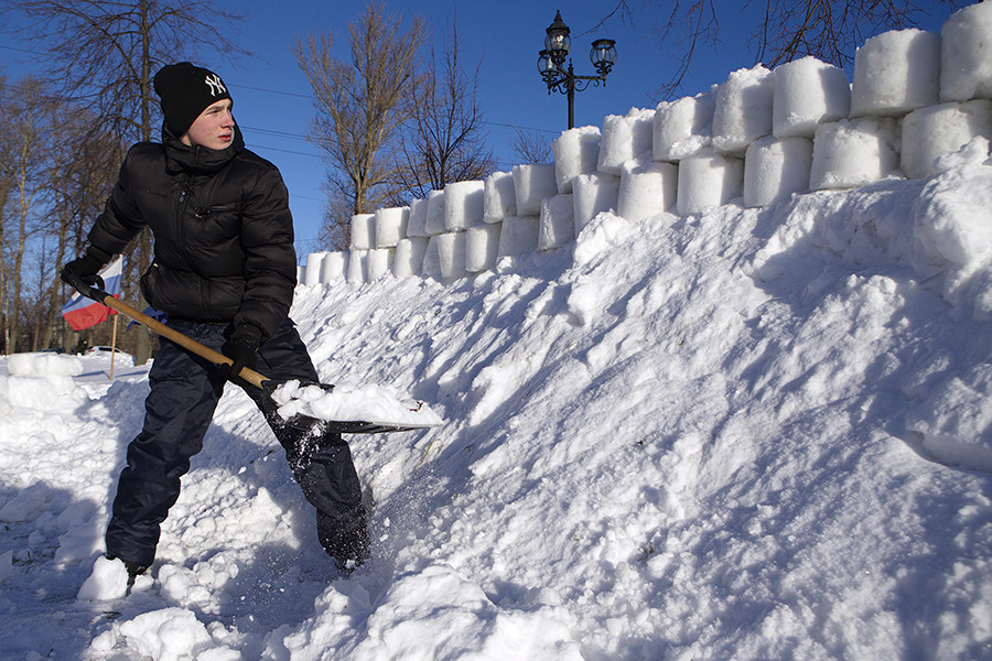 Seorang pemuda membangun benteng salju di Rybinsk.