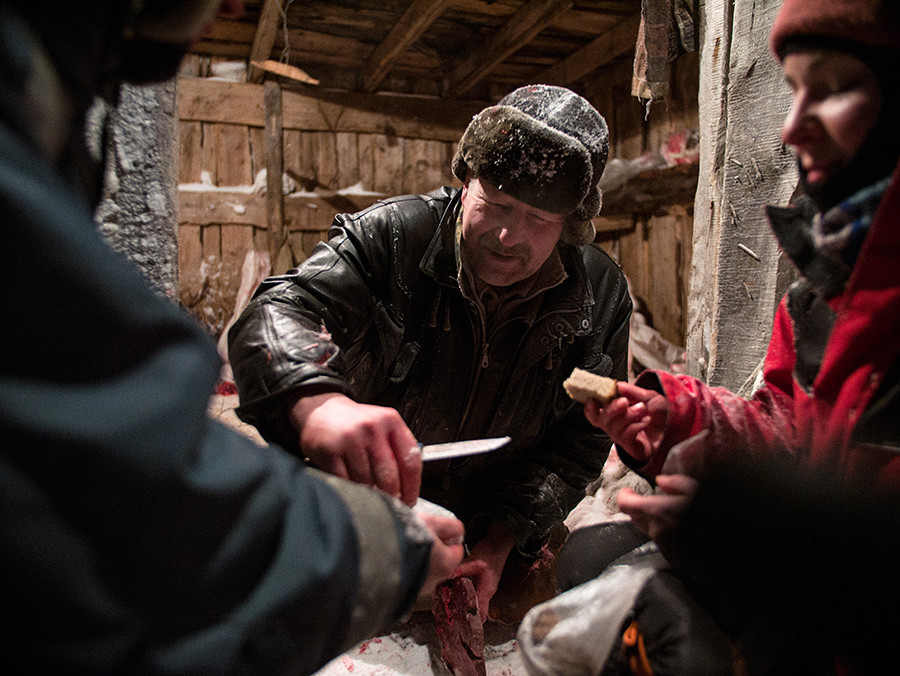 À l’élevage de Polmos, Alexander s’accorde une pause et partage de la moelle et du foie gelé avec les visiteurs, tous accroupis dans la neige.