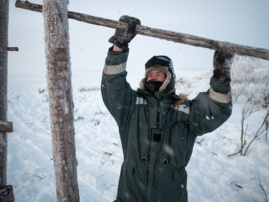 Andréi cierra la barrera después de que los renos hayan sido llevados desde la tundra al prado. A veces pasa semanas o meses solo en la tundra, ocupándose de la manada y reparando las instalaciones de madera.