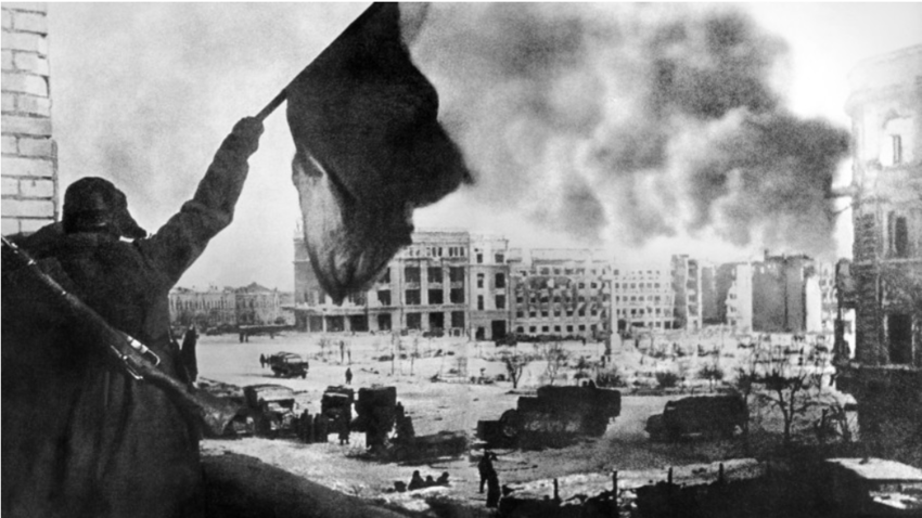Sovjetski vojak maha z rdečo zastavo sred glavnega mestnega trga v Stalingradu. 