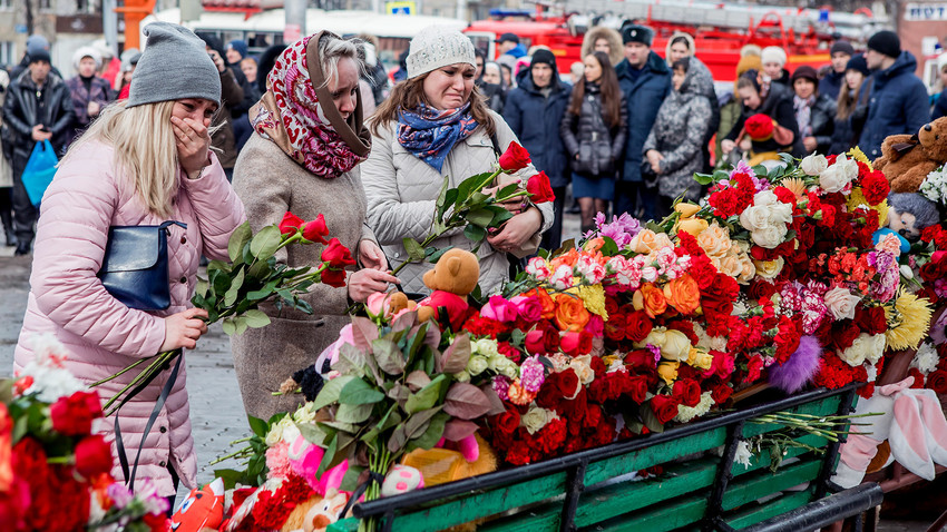 People lay flowers for the victims of a fire in a multi-story shopping center in the Siberian city of Kemerovo, Russia
