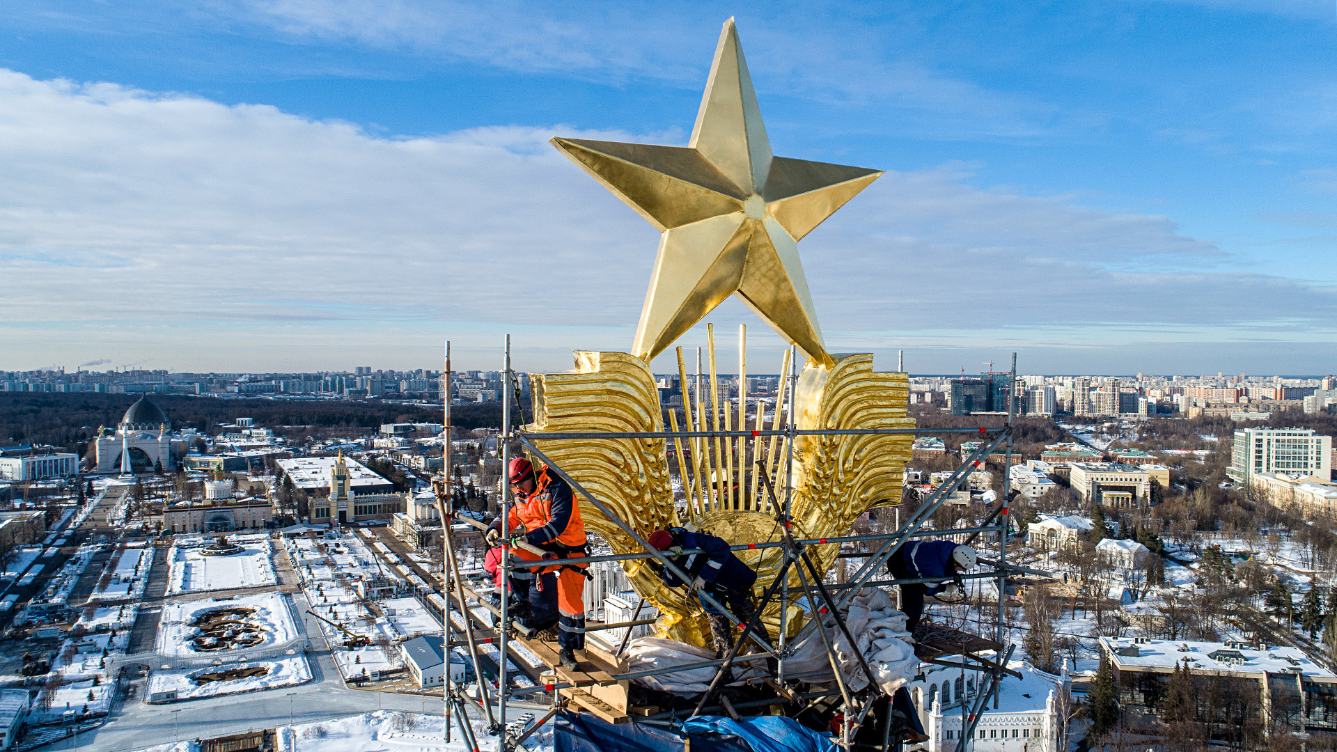 Operai al lavoro per restaurare la stella d'oro nel padiglione centrale del parco VDNKh di Mosca