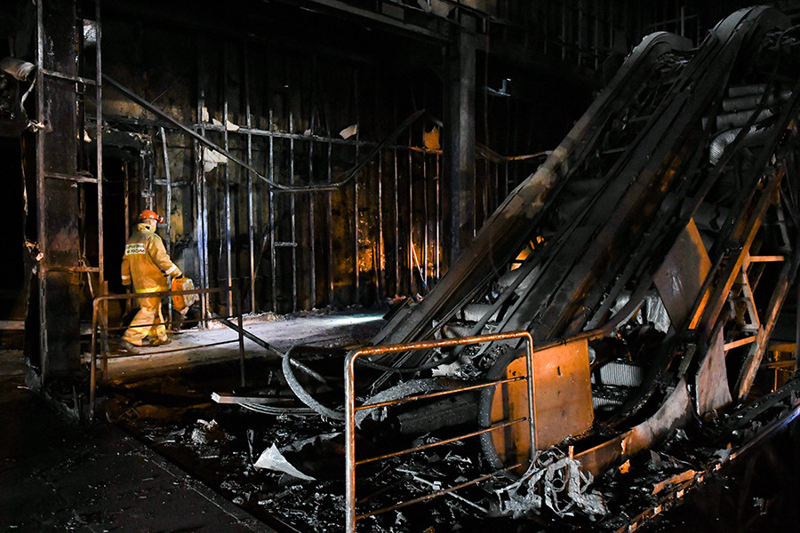 Funcionário do Ministério para Situações de Emergência da Rússia em meio aos escombros de shopping incendiado