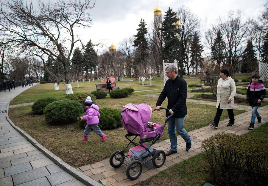 A family walk inside the Kremlin with the Ivan the Great Bell Tower in the background, in Moscow.