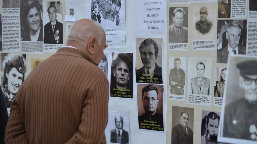 Граѓанин на Скопје ги гледа фотографиите на „Ѕидот на сеќавањето“, изложба во рамките на манифестацијата „Бесмртниот полк“, 2017.